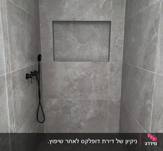 מקלחת עם ראש מקלחת שחור וקירות אריחים אפורים
